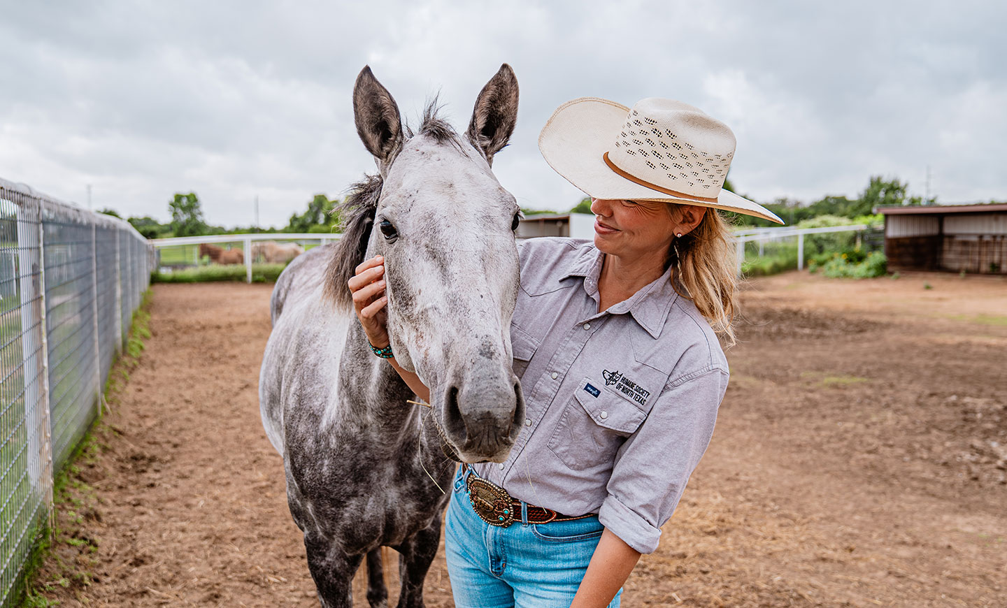 A lady comforting a horse.